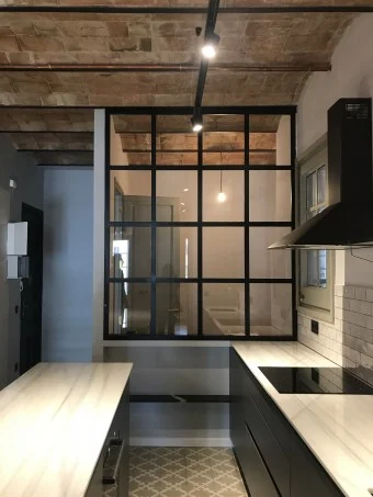Interior de una vivienda reformada con mampara de vidrio y suelo hidráulico