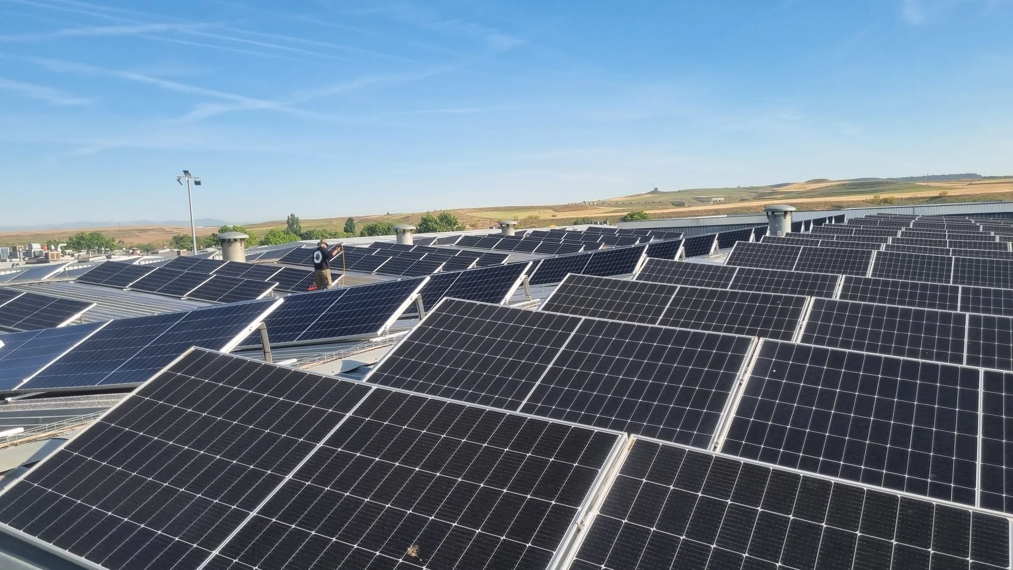 Operario limpiando paneles solares en cubierta industrial